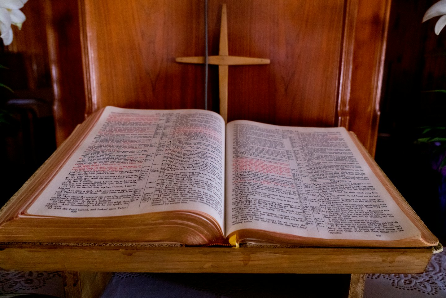 Open Bible on a wooden stand with a wooden cross.