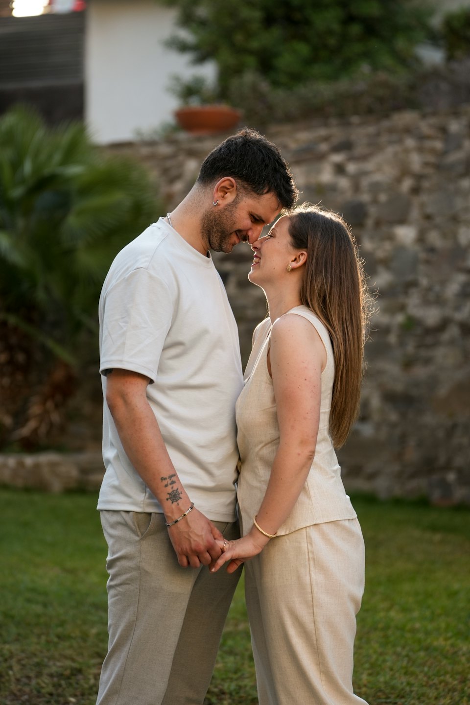 A couple holds hands and smiles at each other outdoors.