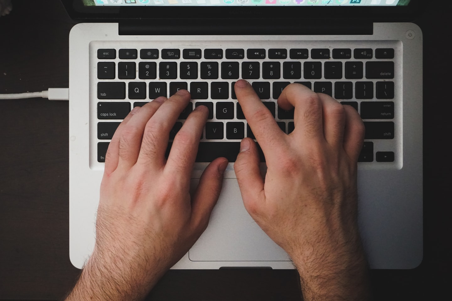 Hands typing on a laptop keyboard with screen visible.