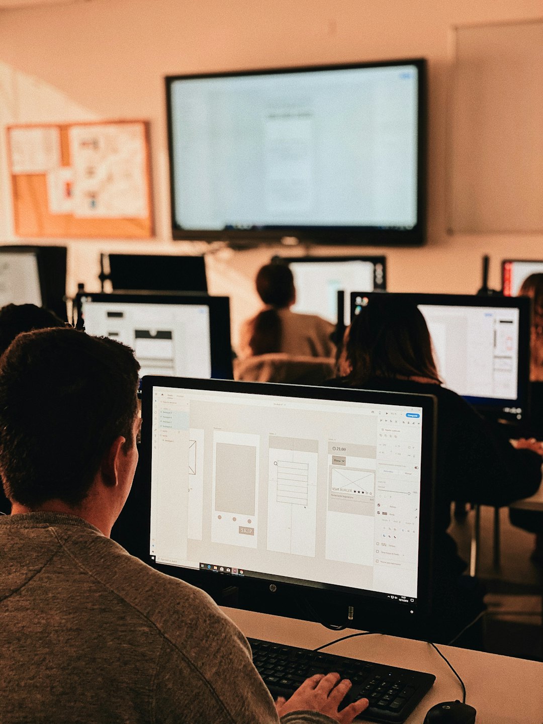 Person working on UI/UX design software on a computer.