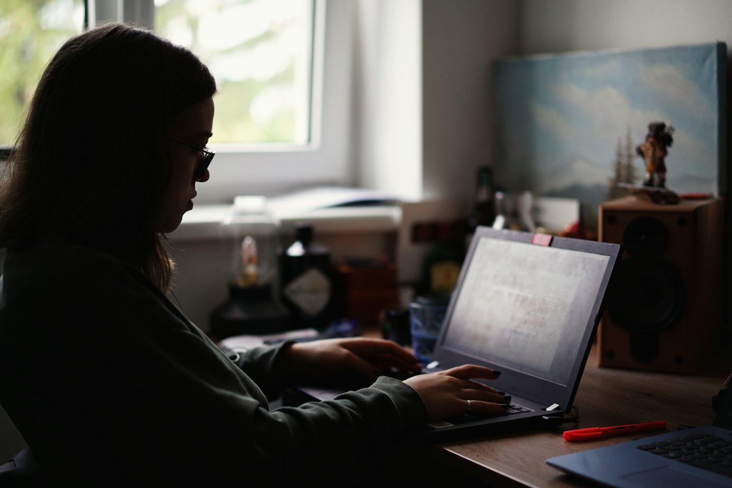 Person working on a laptop at a wooden desk.