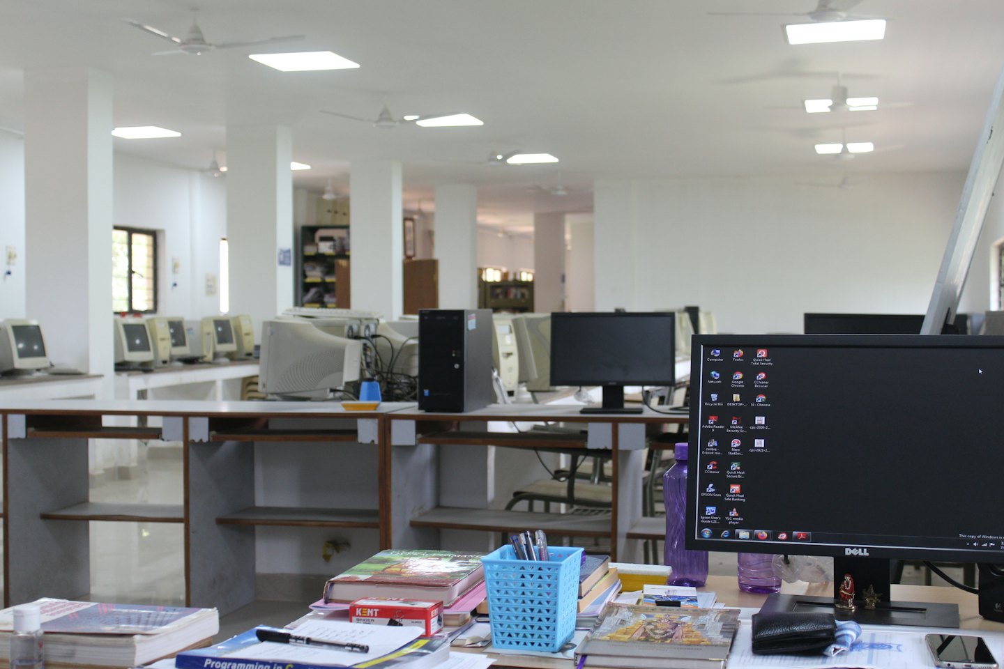 Rows of computer workstations fill a bright classroom.