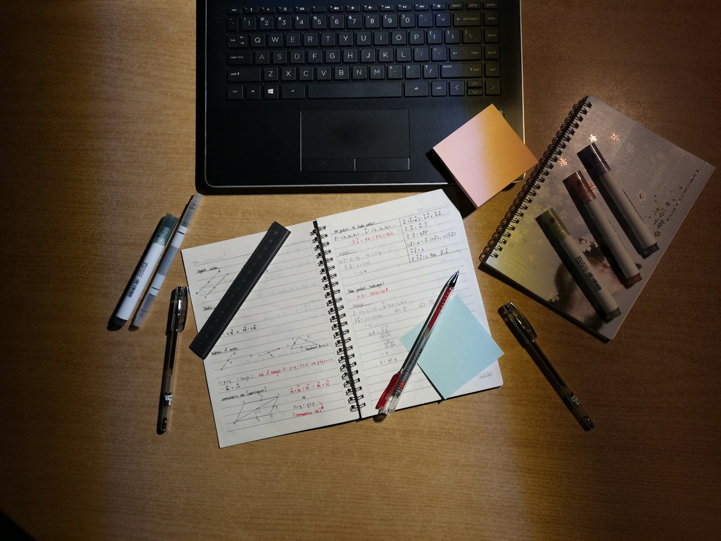 Open laptop and math notebook on a wooden desk.