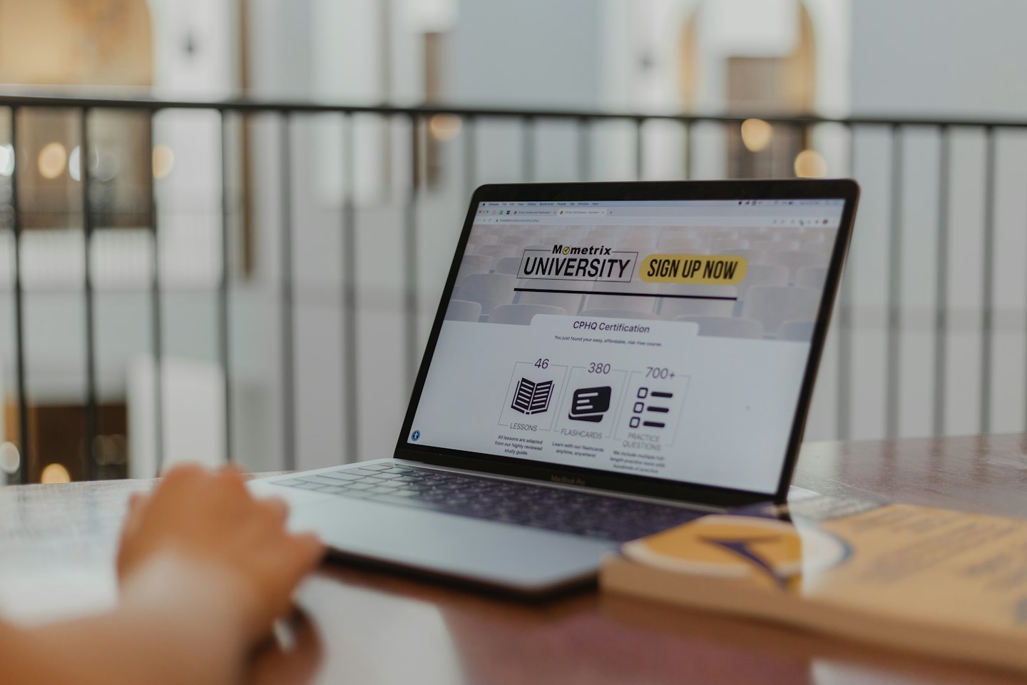 Hand resting on laptop showing Mometrix University website.